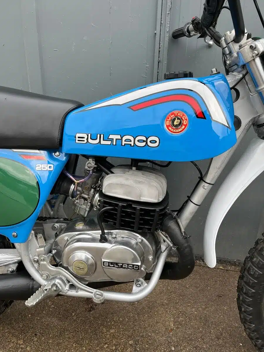Restaurierte Bultaco Pursang MK10 250cc von 1977 mit blauem Tank und sichtbaren Motordetails.