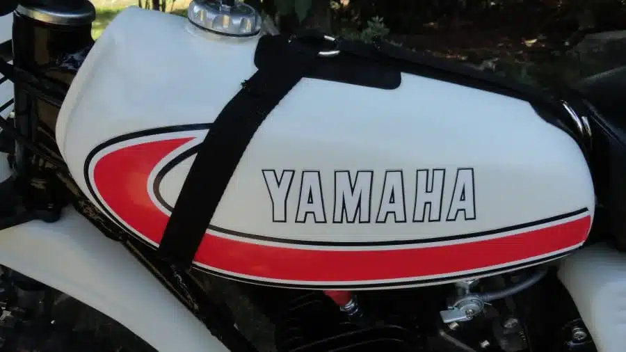 Kraftstofftank einer 1977 Yamaha YZ80D mit traditionellen roten und schwarzen Verzierungen sowie gut sichtbarem Yamaha-Logo.