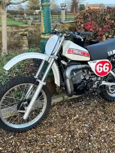 Seitenansicht einer restaurierten weißen Yamaha YZ400E von 1978 mit Startnummer 66 im Außenbereich