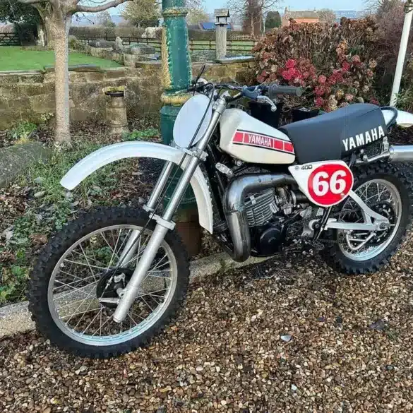 Seitenansicht einer restaurierten weißen Yamaha YZ400E von 1978 mit Startnummer 66 im Außenbereich