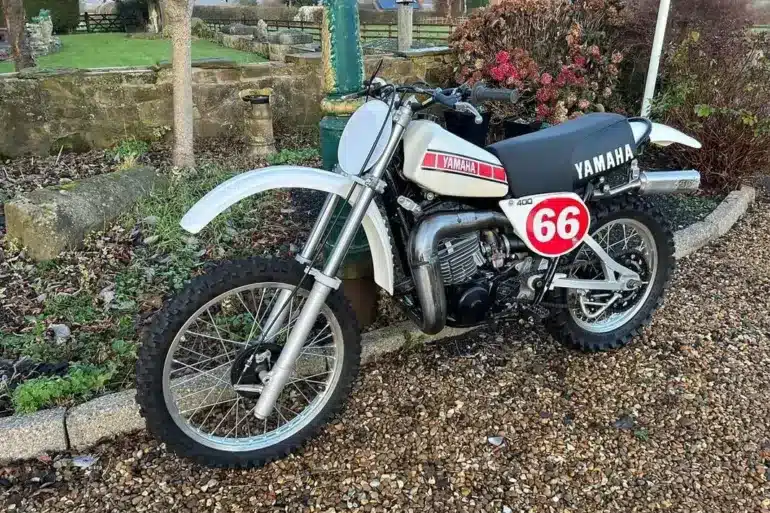 Seitenansicht einer restaurierten weißen Yamaha YZ400E von 1978 mit Startnummer 66 im Außenbereich