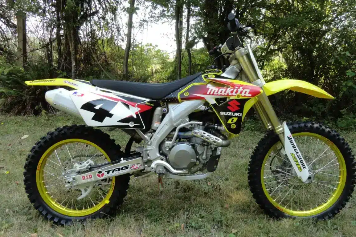 Suzuki RM-Z450 Ricky Carmichael Special Edition 2007 im Makita-Werkstrim auf einer Wiese, linksseitige Ansicht.