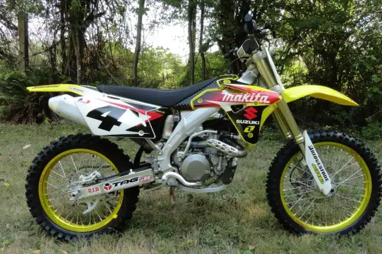 Suzuki RM-Z450 Ricky Carmichael Special Edition 2007 im Makita-Werkstrim auf einer Wiese, linksseitige Ansicht.