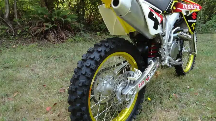 Nahaufnahme des Hinterrads einer Suzuki RM-Z450 Ricky Carmichael Special Edition 2007 mit gelbem Felgenbett und Crossreifen auf einer Wiese