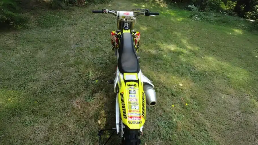 Heckansicht der gelben Suzuki RM-Z450 Ricky Carmichael Special Edition (2007) mit Startnummer, Aufklebern und Rennaufbau auf einer Wiese.