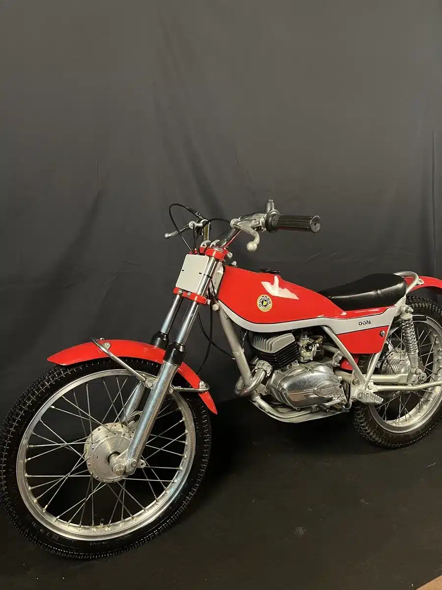 Seitenansicht einer restaurierten roten Bultaco Chispa 50 von 1980 vor schwarzem Hintergrund