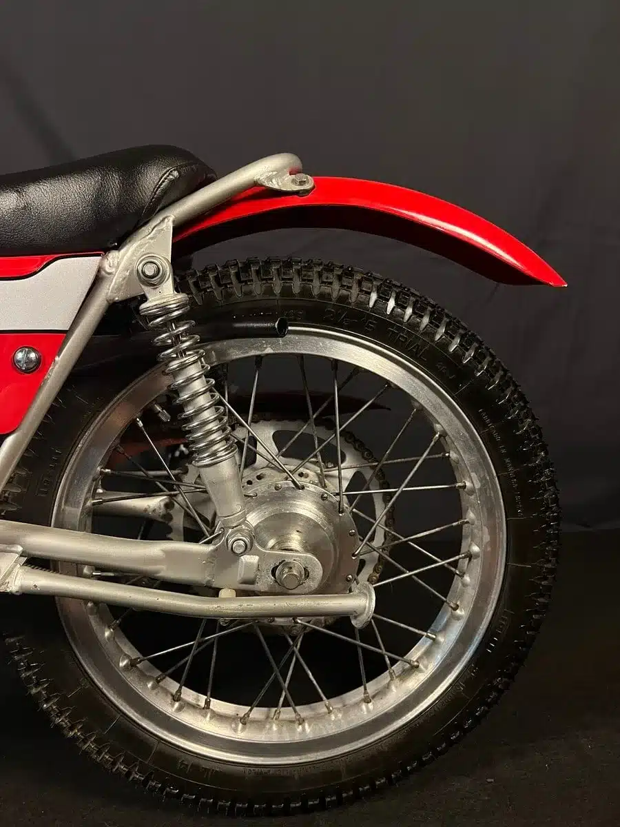 Hinterrad, Federbein und roter Kotflügel einer restaurierten Bultaco Chispa 50 von 1980 im Detail.