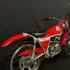 Restaurierte Bultaco Chispa 50 von 1980 in Rot, fotografiert von schräg hinten vor schwarzem Hintergrund.
