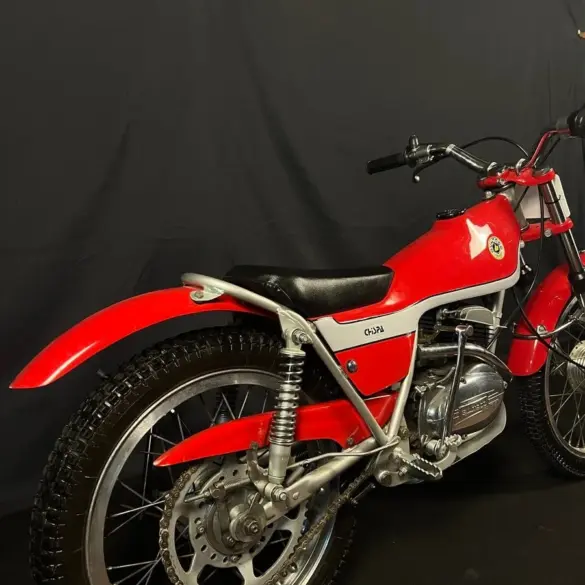 Restaurierte Bultaco Chispa 50 von 1980 in Rot, fotografiert von schräg hinten vor schwarzem Hintergrund.