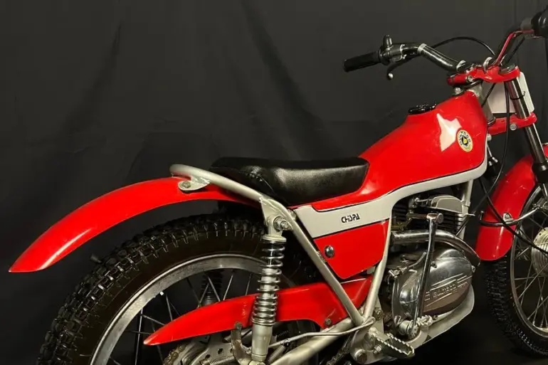 Restaurierte Bultaco Chispa 50 von 1980 in Rot, fotografiert von schräg hinten vor schwarzem Hintergrund.