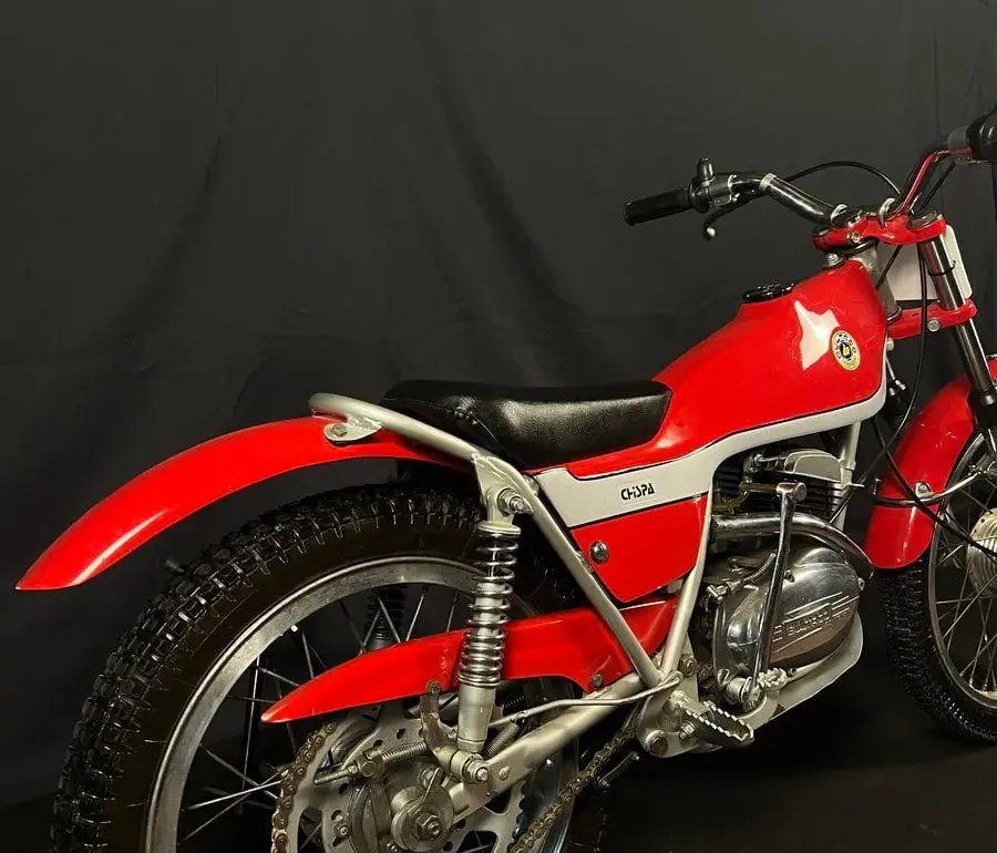 Restaurierte Bultaco Chispa 50 von 1980 in Rot, fotografiert von schräg hinten vor schwarzem Hintergrund.