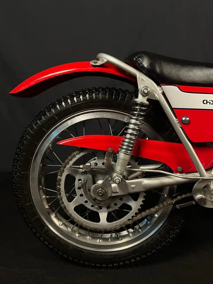 Detailansicht des Hinterrads einer roten Bultaco Chispa 50 von 1980 mit Kettentrieb und Federung