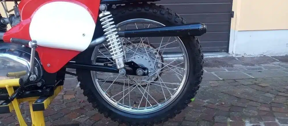 Nahaufnahme des Hinterrads einer restaurierten Gilera-Bessone 175 von 1970, mit Stollenreifen und Doppelfederung.