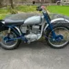 Seitenansicht einer blauen Greeves Hawkstone MCS 250cc von 1960, klassisches britisches Offroad-Motorrad mit periodentypischen Details.