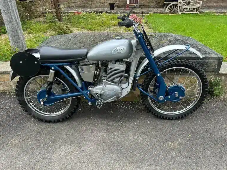 Seitenansicht einer blauen Greeves Hawkstone MCS 250cc von 1960, klassisches britisches Offroad-Motorrad mit periodentypischen Details.