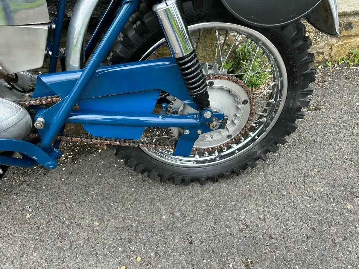 Detailansicht vom Hinterrad, Kette und Hinterradaufhängung einer blauen Greeves Hawkstone MCS 250cc von 1960.