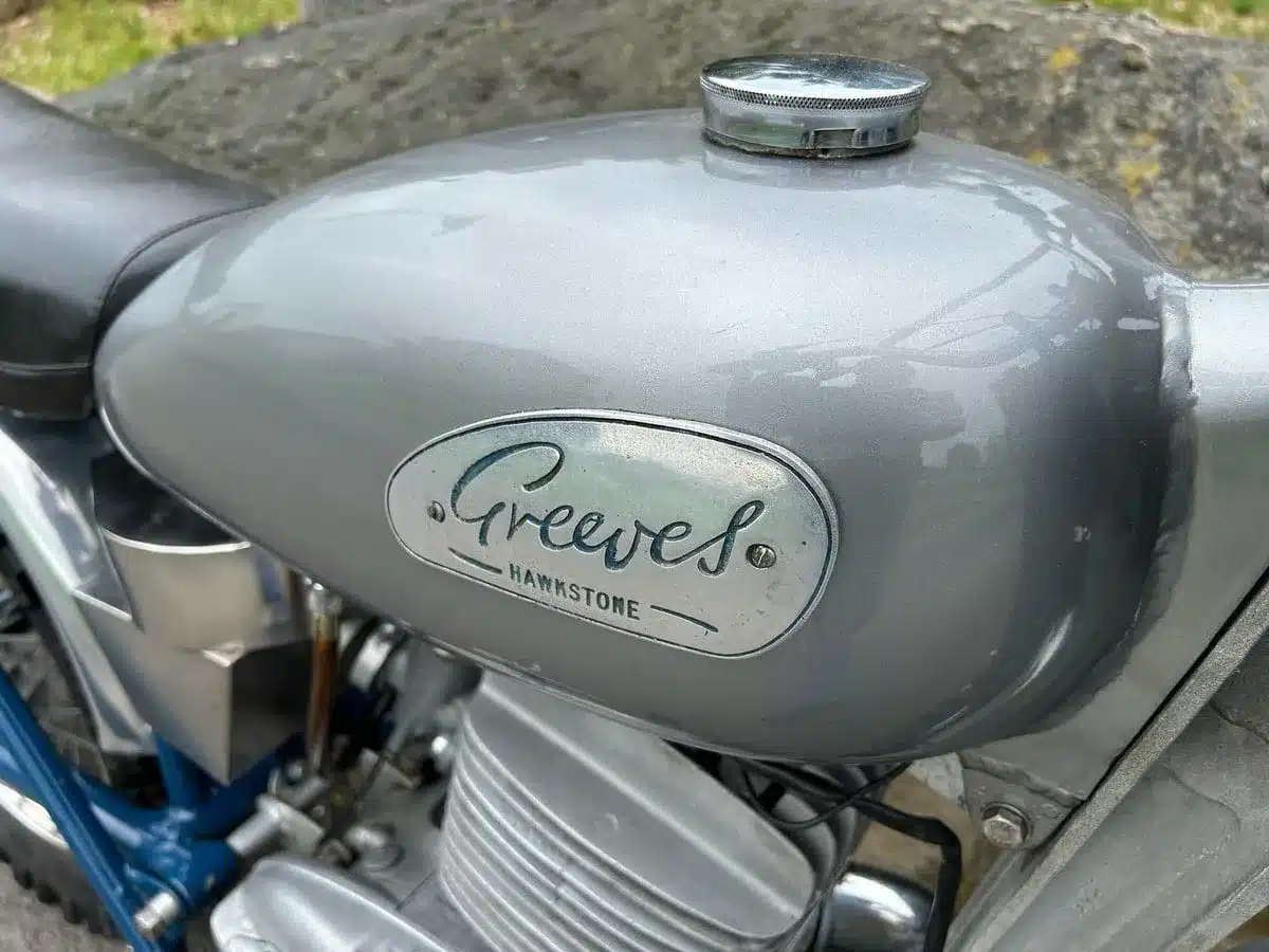 Nahaufnahme des Kraftstofftanks einer Greeves Hawkstone MCS 250cc von 1960 mit sichtbarem Markenlogo.