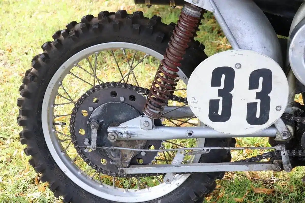 Hinterrad mit Twin-Shock-Federung und Startnummer einer Husqvarna 250 Cross von 1967 auf Gras