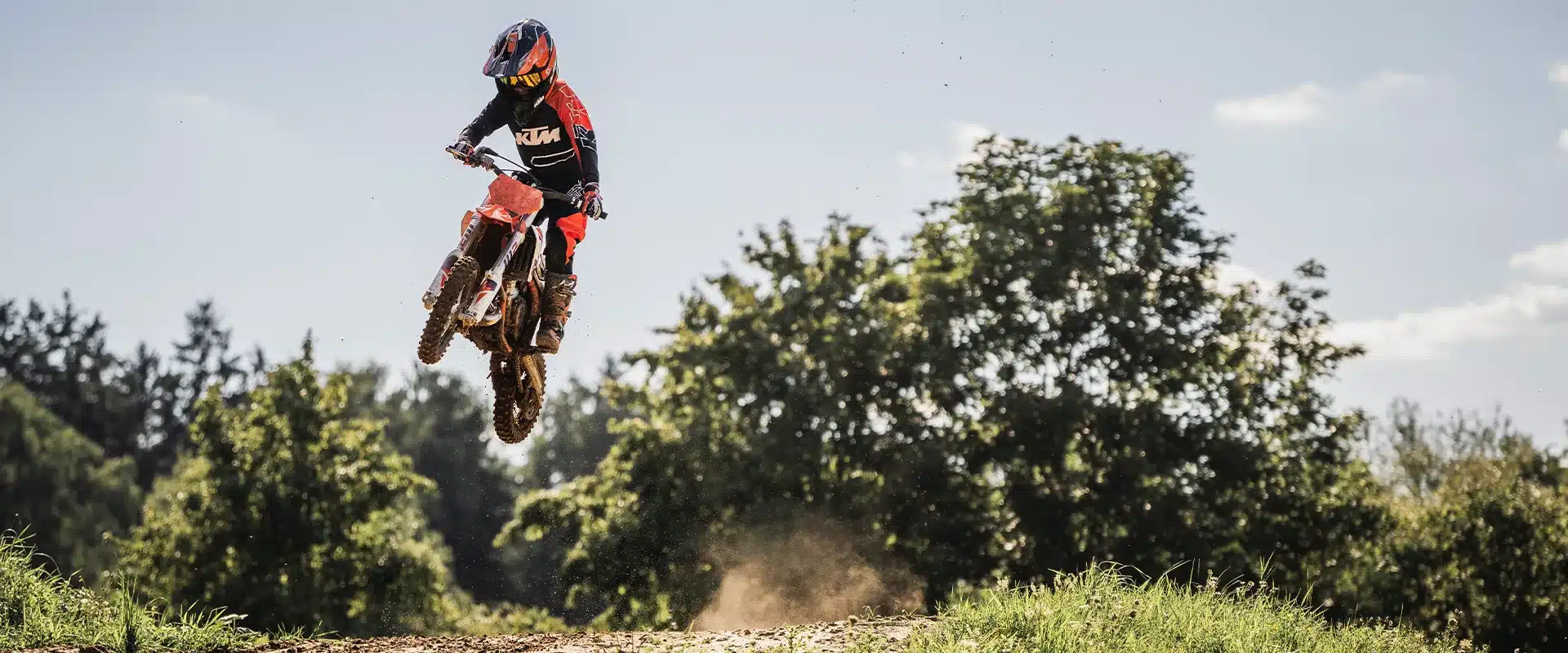 Motocross-Bike KTM 50 SX 2026 mit jungem Fahrer bei einem Sprung auf einer Offroad-Strecke.