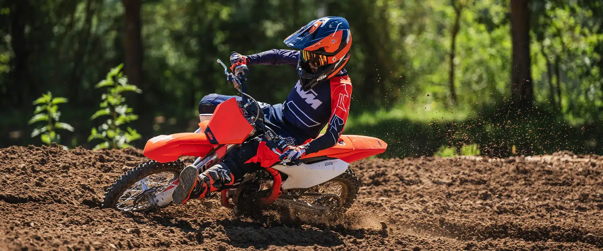 2026 KTM 65 SX Motocross-Motorrad im Einsatz auf einer Offroad-Strecke, Pilot in voller Schutzkleidung.