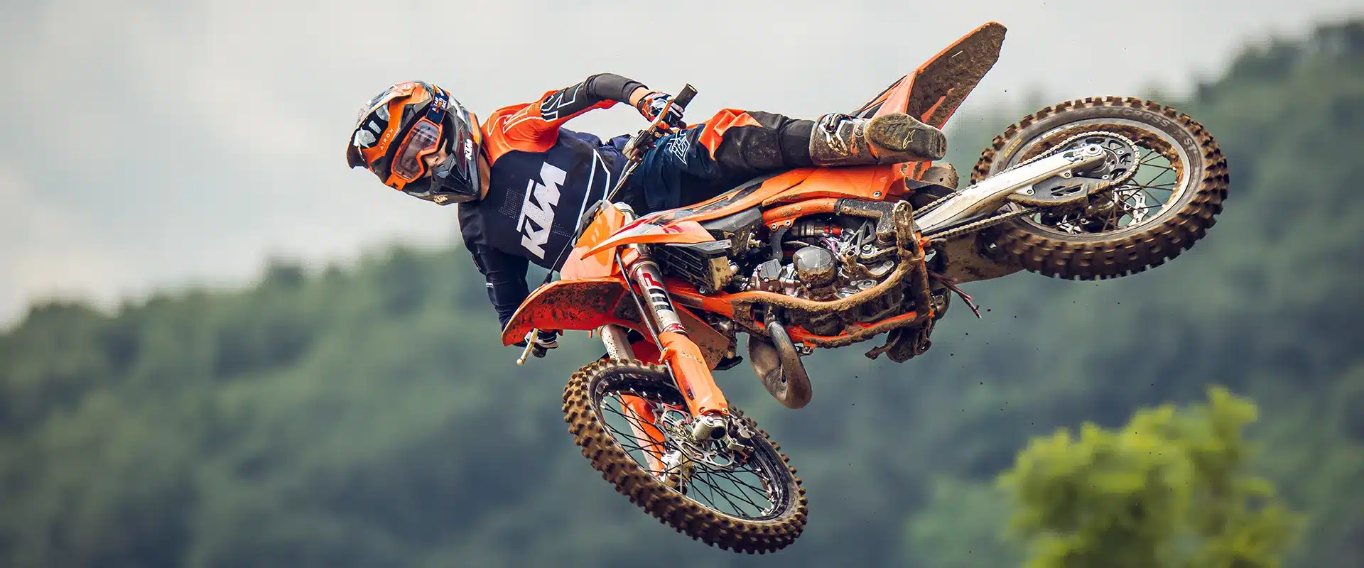 Jugendlicher Fahrer springt mit einer KTM 85 SX 17/14 Motocross-Maschine über eine Strecke im Gelände.