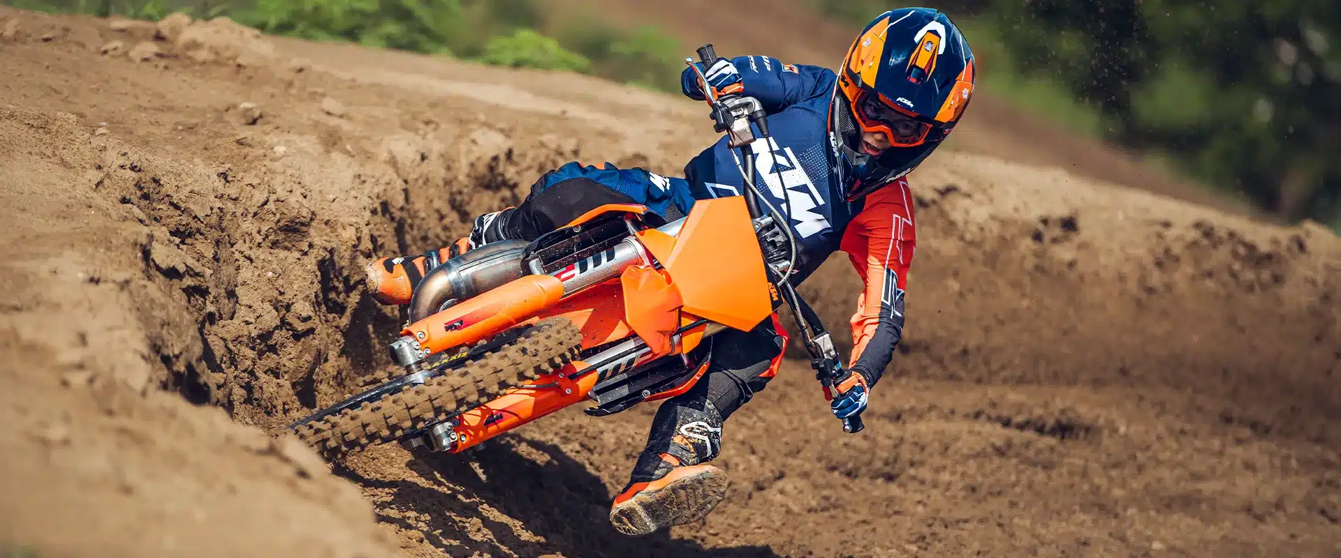 Junger Motocross-Fahrer mit KTM 85 SX 17/14 fährt dynamisch durch eine Kurve auf einer Sandstrecke