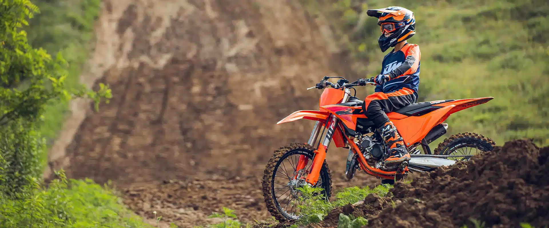 Junger Fahrer mit KTM 85 SX 19/16 2026 Motocross-Motorrad im Gelände, Seitenansicht.