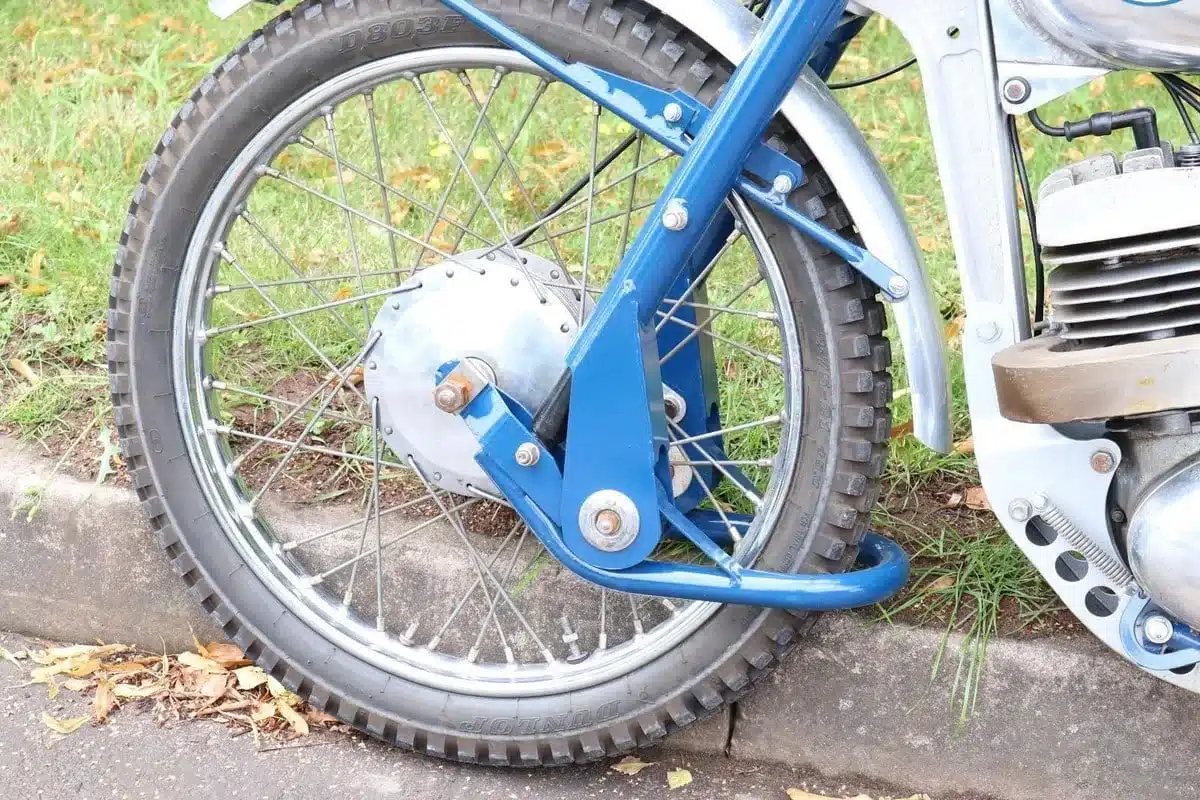 Vorderrad eines Motorrads mit blauer Gabel und Trommelbremse am Straßenrand