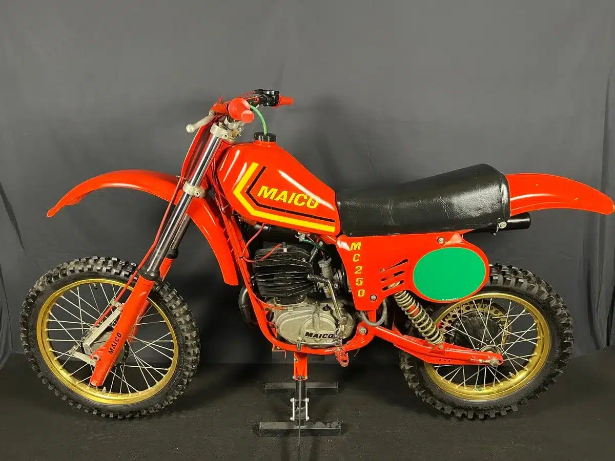 Rote Maico MC 250 Motocross-Maschine von 1980 mit originalen Teilen, seitlich fotografiert vor schwarzem Hintergrund.