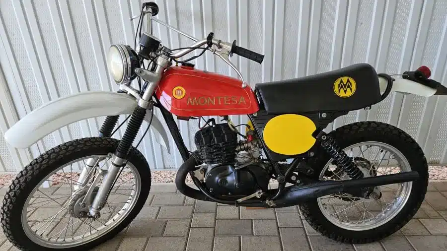 Seitenansicht einer Montesa Enduro 250, Baujahr 1975, mit rotem Tank, schwarzem Sitz und gelben Nummerntafeln, klassische Enduro-Ausführung mit Trommelbremsen und Telegabel.