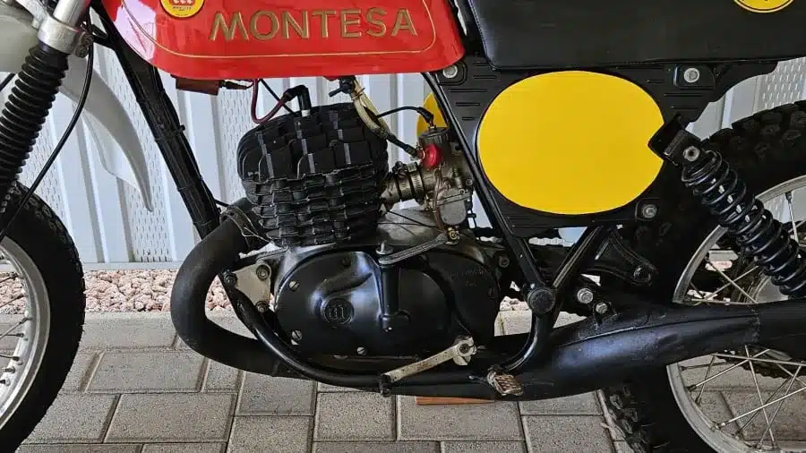 Detailaufnahme des Motors und Rahmens einer Montesa Enduro 250 von 1975, mit rotem Tank und gelbem Seitendeckel.