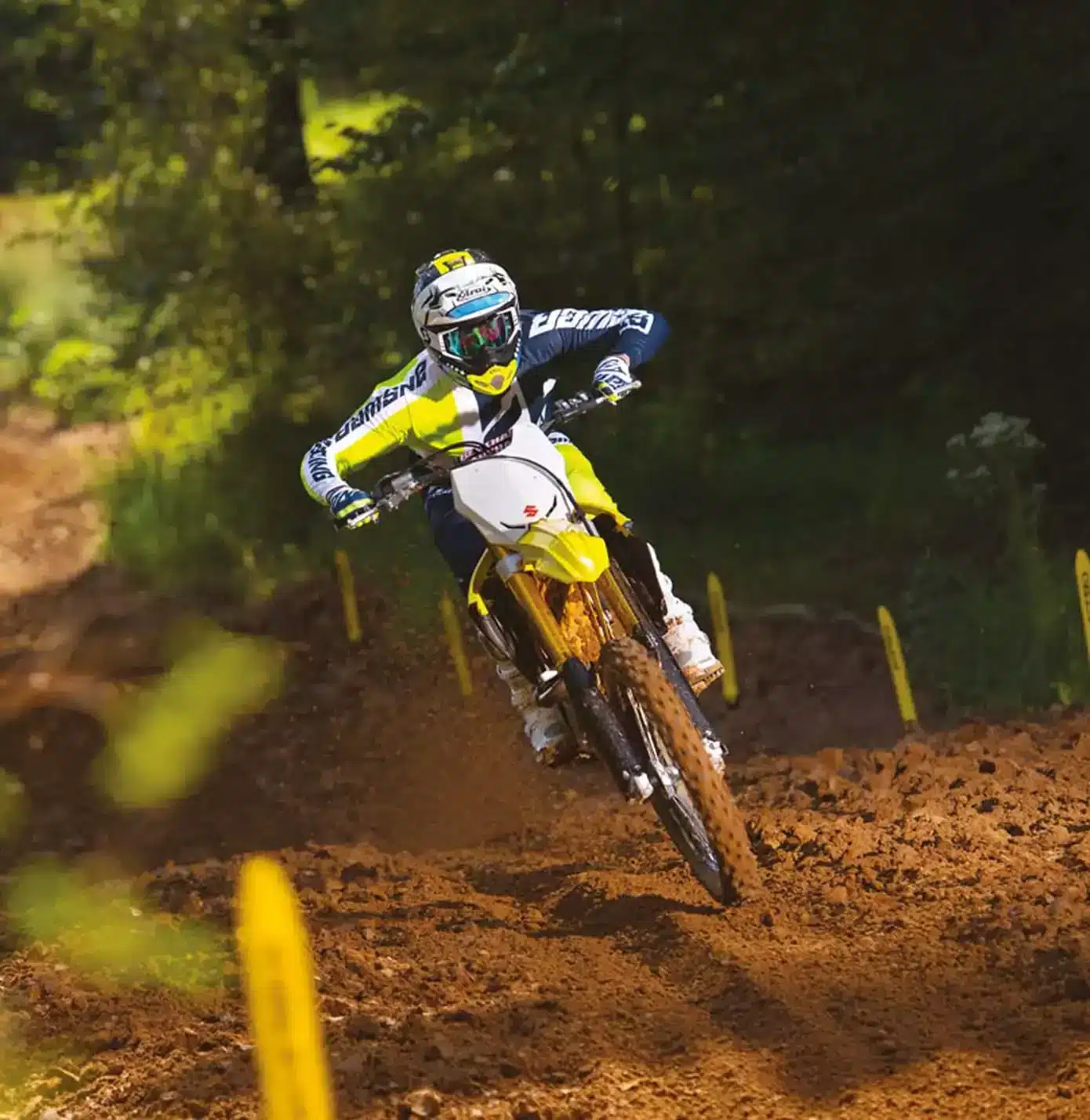 Motocross-Fahrer fährt Suzuki RM-Z450 im Gelände bei hoher Geschwindigkeit.