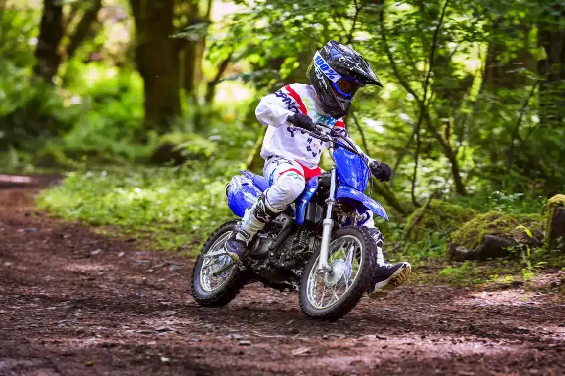 Jugendlicher auf einer Yamaha TT-R110 fährt Offroad durch einen Wald