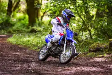 Jugendlicher auf einer Yamaha TT-R110 fährt Offroad durch einen Wald