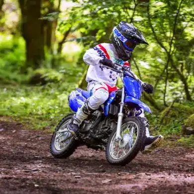 Jugendlicher auf einer Yamaha TT-R110 fährt Offroad durch einen Wald