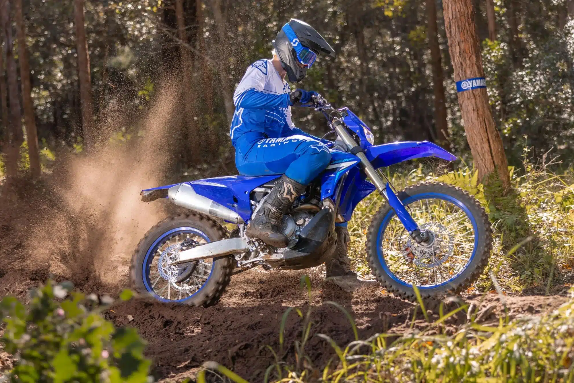 Yamaha WR450F Enduro-Motorrad im Gelände mit Fahrer in voller Ausrüstung, wirbelt Staub auf.