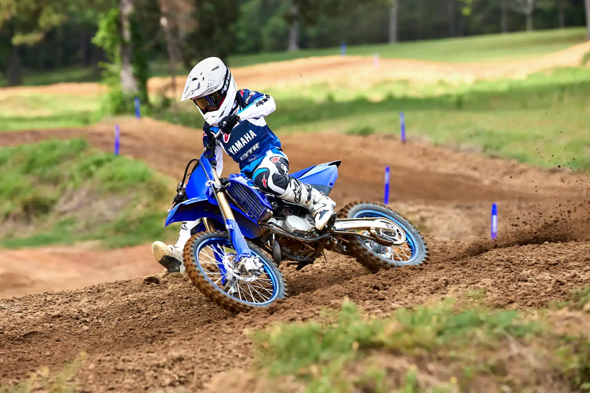 Motocross-Fahrer auf einer Yamaha YZ250 in typischem Icon Blue beim Fahren auf einer schlammigen Strecke.