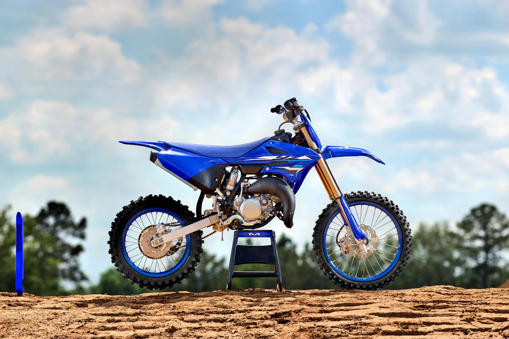 Yamaha YZ250 Zweitakt-Motocross-Motorrad in Seitenansicht auf sandigem Untergrund vor blauem Himmel