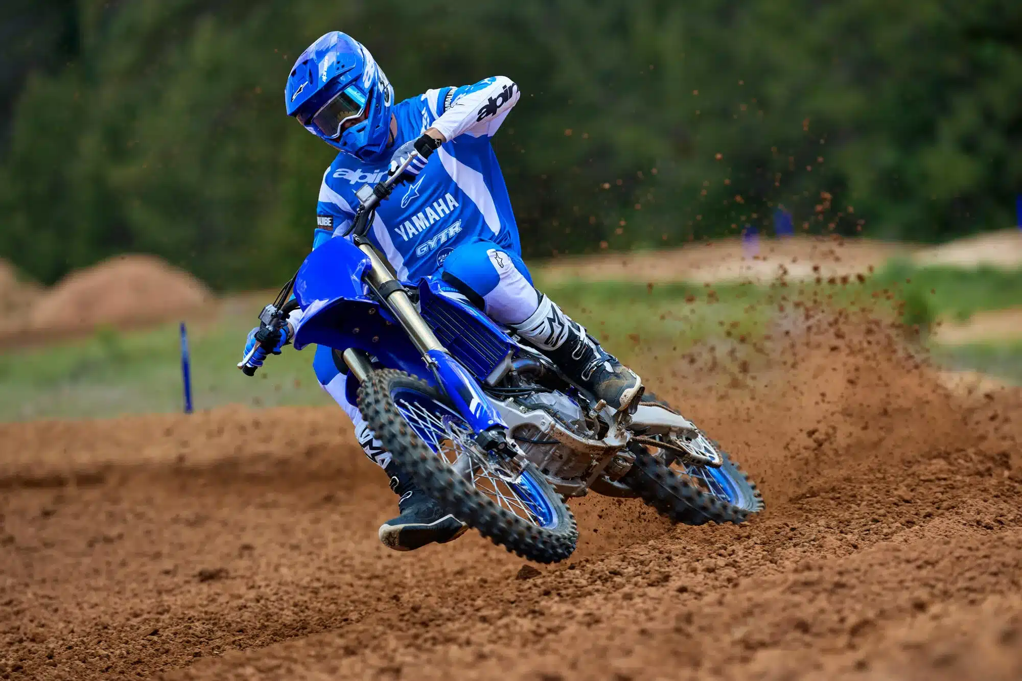 Fahrer mit blauer Ausrüstung fährt eine Yamaha YZ450F 2026 über eine Motocross-Piste und wirbelt Erde auf