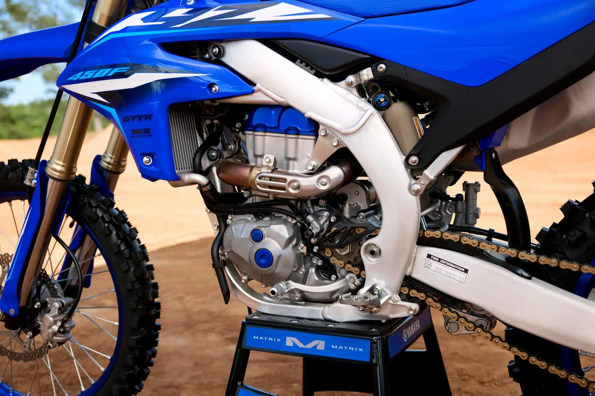 Motor und Rahmen der Yamaha YZ450F 2026, Nahaufnahme mit sichtbarem Aluminiumrahmen und Motorkomponenten auf sandigem Offroad-Untergrund.