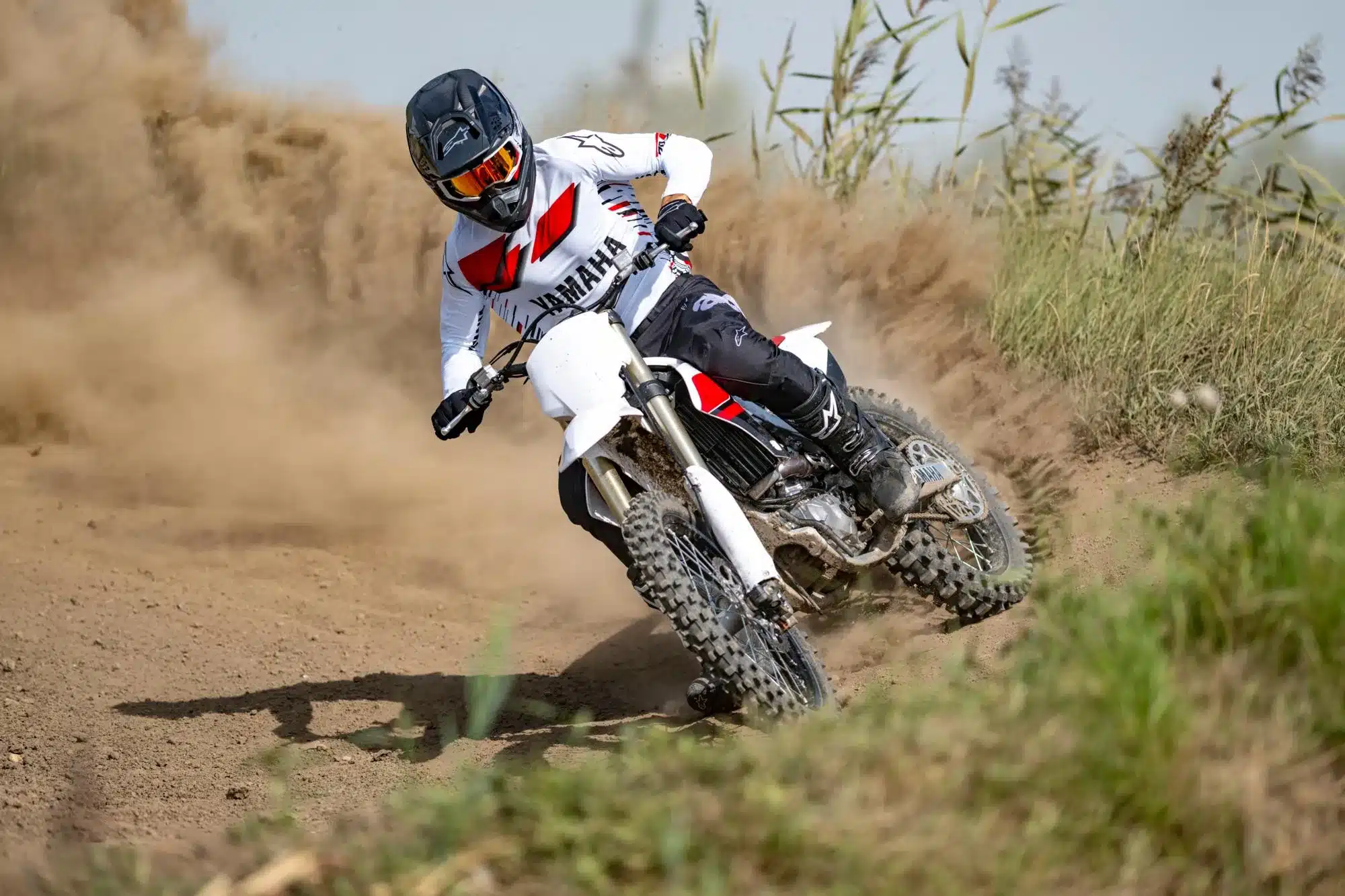 Motocross-Fahrer auf Yamaha YZ450F 70th Anniversary Edition fährt auf sandiger Offroad-Strecke.