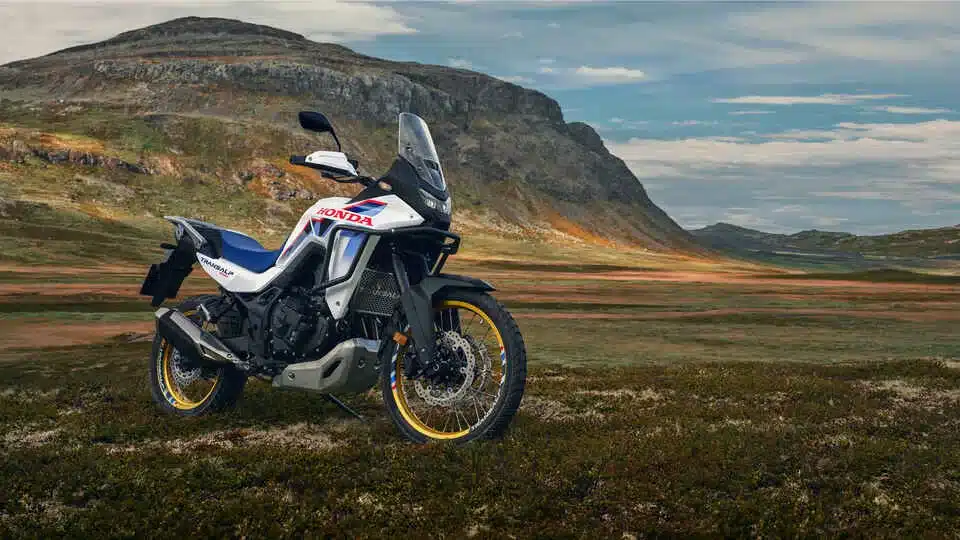 Honda XL750 Transalp Motorrad auf einer Wiese vor Bergen