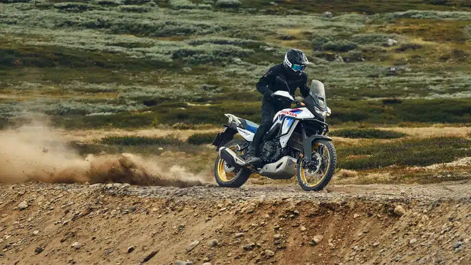 Honda XL750 Transalp Adventure-Motorrad fährt auf einer Schotterstraße in bergiger Landschaft