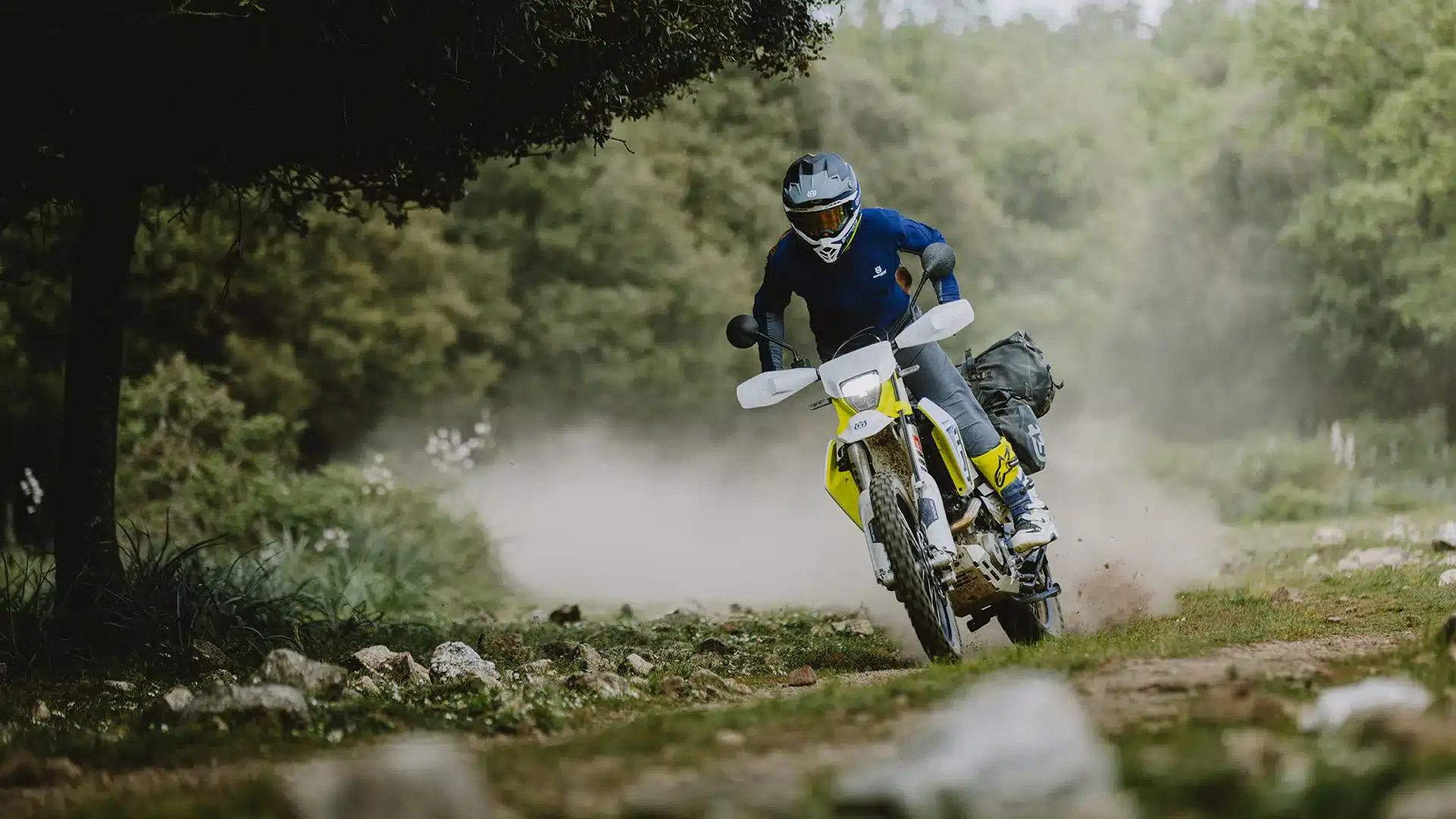 Ein Fahrer bewegt die Husqvarna 701 Enduro 2026 dynamisch über einen steinigen Waldpfad.