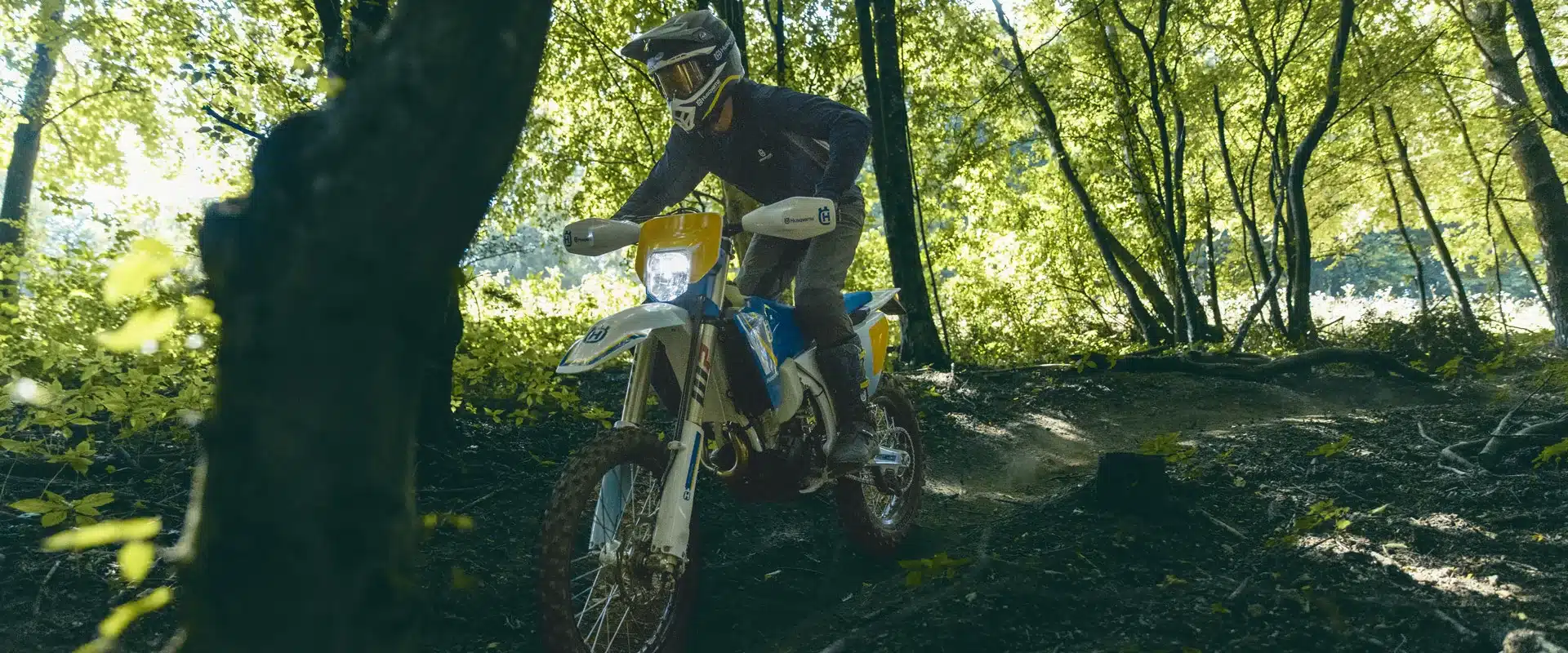 Husqvarna FE 501 Heritage Enduro-Motorrad wird von einem Fahrer im Wald über einen wurzeligen Boden gesteuert