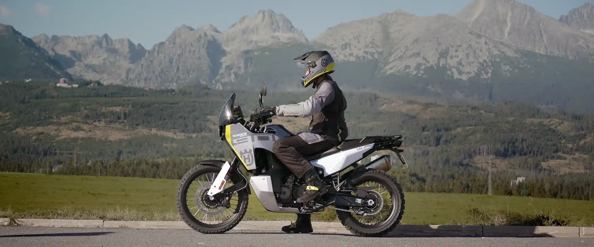 Husqvarna Norden 901 Reiseenduro mit Fahrer vor Bergkulisse, Seitenansicht