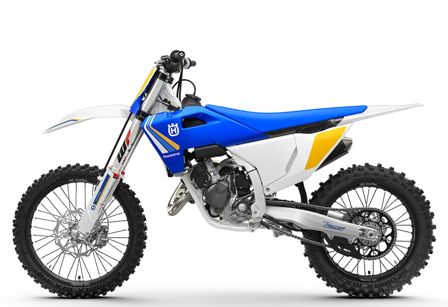 Seitenansicht der Husqvarna TC 125 Heritage 2025 mit blauer, weißer und gelber Verkleidung auf weißem Hintergrund.