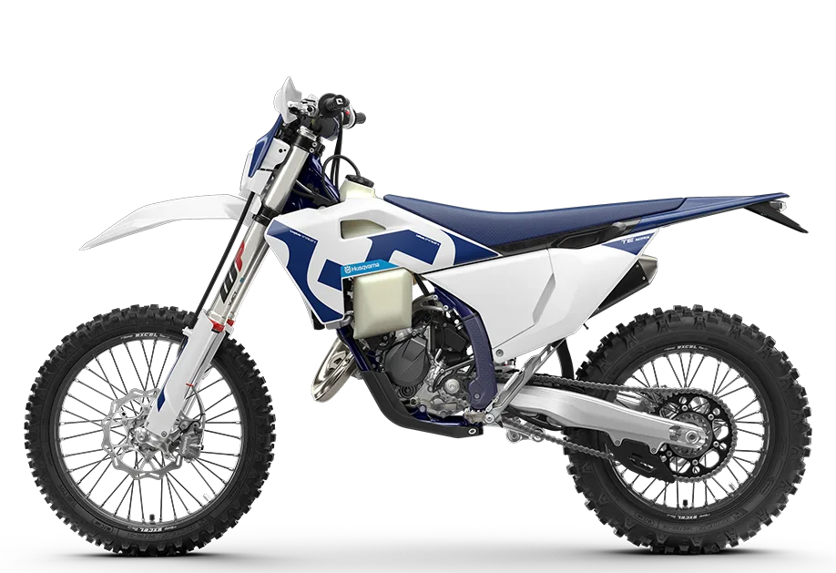 Seitenansicht der Husqvarna TE 125 2026, ein leichtes Enduro-Motorrad mit blau-weißer Verkleidung auf Stollenreifen.