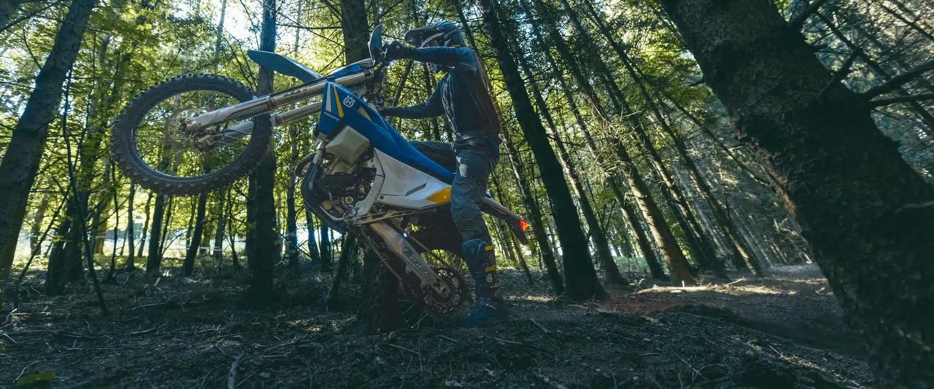 Ein Fahrer fährt eine Husqvarna TE 300 Heritage Enduro im Wald über eine steile Passage.