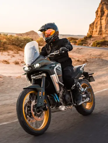 KOVE 800X PRO Adventure-Motorrad fährt auf einer asphaltierten Straße durch felsige Wüstenlandschaft